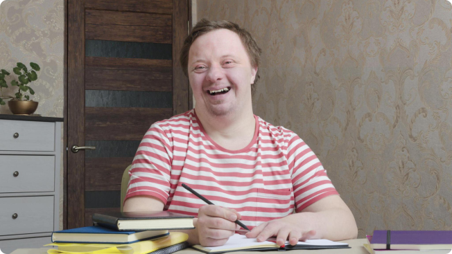 Young man smiling holding a pencil with a book